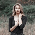 Beautiful young blonde girl in a black T-shirt in a field near