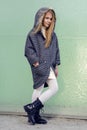 Beautiful young blonde girl in a coat and boots posing for fashion,
