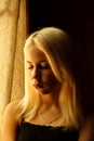 Beautiful young blonde girl. Dramatic portrait of a woman in the dark. Dreamy female look in twilight. Female silhouette.