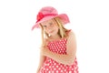 Beautiful young blonde girl with enigmatic smile wearing big pink floppy hat and a polka dot dress. Isolated on white studio Royalty Free Stock Photo