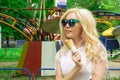 Beautiful, young blonde girl with ice cream in her hands, licks the ice cream on the background of a green park. Italian ice cream Royalty Free Stock Photo