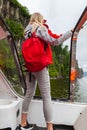 Beautiful young blonde girl in an orange life jacket standing on the edge and looking far in a motor boat during an excursion and