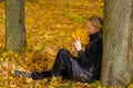 A beautiful young blonde girl sits on fallen autumn leaves in the park Royalty Free Stock Photo