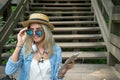 Beautiful young blonde hipster woman with glasses looking at camera in the Park with tablet in hand, sitting on the Royalty Free Stock Photo