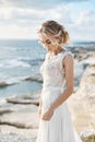 Beautiful young blonde model woman with nude makeup in a fashionable wedding dress walking at the sea coast at Cyprus Royalty Free Stock Photo