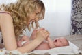 Beautiful young blonde mother is playing with her newborn baby in bed. Mom and her Child. Early development of an Royalty Free Stock Photo