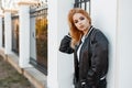 Beautiful young blonde woman in a black summer stylish jacket in black jeans in a white polo shirt standing near a vintage metal Royalty Free Stock Photo