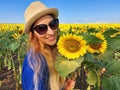 A beautiful young blonde woman in a blue T-shirt, wearing hat, enjoy nature in the sunflower field at sunrise Royalty Free Stock Photo