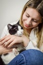 Beautiful young blonde woman cuddling a bored young black and white cat