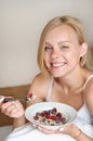 Beautiful young blonde woman eating her oatmeal with berries for breakfast in the morning Royalty Free Stock Photo