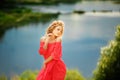 Beautiful young blonde woman with a flower wreath on her head. Beauty girl with flowers hairstyle in a red long dress near the Royalty Free Stock Photo