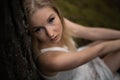 Close up portrait - Beautiful young blonde woman forest nymph in white dress in evergreen wood Royalty Free Stock Photo