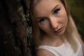 Close up portrait - Beautiful young blonde woman forest nymph in white dress in evergreen wood Royalty Free Stock Photo