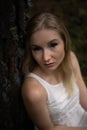 Close up portrait - Beautiful young blonde woman forest nymph in white dress in evergreen wood Royalty Free Stock Photo