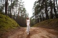 Walking Beautiful young blonde woman forest nymph in white dress in evergreen wood Royalty Free Stock Photo