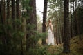 Walking Beautiful young blonde woman forest nymph in white dress in evergreen wood Royalty Free Stock Photo