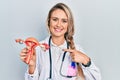 Beautiful young blonde woman holding anatomical model of female genital organ smiling happy pointing with hand and finger Royalty Free Stock Photo