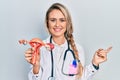 Beautiful young blonde woman holding anatomical model of female genital organ smiling happy pointing with hand and finger to the Royalty Free Stock Photo
