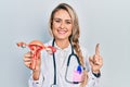 Beautiful young blonde woman holding anatomical model of female genital organ smiling with an idea or question pointing finger Royalty Free Stock Photo