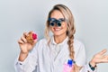 Beautiful young blonde woman holding geode stone wearing magnifier glasses celebrating achievement with happy smile and winner