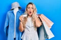 Beautiful young blonde woman holding shopping bags and credit card afraid and shocked with surprise and amazed expression, fear Royalty Free Stock Photo