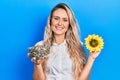 Beautiful young blonde woman holding sunflower seeds an flower smiling with a happy and cool smile on face Royalty Free Stock Photo