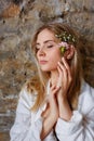 A beautiful young blonde woman holds carnation and gypsophila flowers in her hands near her face