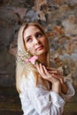 A beautiful young blonde woman holds carnation and gypsophila flowers in her hands near her face