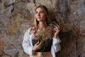 A beautiful young blonde woman holds carnation and gypsophila flowers in her hands near her face