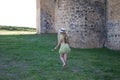 A beautiful young blonde woman with long hair walks barefoot on the fresh green grass next to a castle. The woman wears a hat and Royalty Free Stock Photo