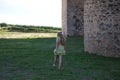 A beautiful young blonde woman with long hair walks barefoot on the fresh green grass next to a castle. The woman wears a hat and Royalty Free Stock Photo