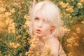 Beautiful young blonde woman on the meadow with yellow flowers on a warm summer day Royalty Free Stock Photo