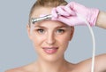 Beautiful young blonde woman with nude makeup,clean fresh skin naked shoulders holds a nozzle for microdermabrasion in her hands.