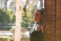 Beautiful young blonde woman with a ponytail in her hair leaning against a red brick wall and holding on to a fence. In the Royalty Free Stock Photo