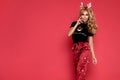 Beautiful young blonde woman is posing in a Christmas satin pajama on red background. Nightwear. Pajamas fashion. Christmas