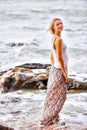 Beautiful young blonde woman posing outdoor at the rocky sea shore