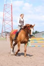 Beautiful young blonde woman riding chestnut horse