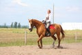 Beautiful young blonde woman riding chestnut horse