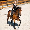 Beautiful young blonde woman riding a horse