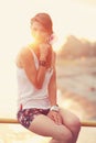 Beautiful young blonde woman sitting on the beach. Wearing white T-shirt. Wind is blowing into her long blonde hair. In Royalty Free Stock Photo