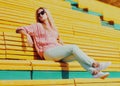Beautiful young blonde woman sitting on bench in a city park Royalty Free Stock Photo