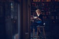 Beautiful young blonde woman sitting in a cozy cafe with bookshelves drinking coffee Royalty Free Stock Photo
