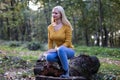 Young blonde woman sitting on a tree branch in the forest Royalty Free Stock Photo