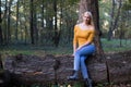 Young blonde woman sitting on a tree branch in the forest Royalty Free Stock Photo