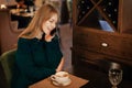 Beautiful young blonde woman smiles at coffee shop and talks on phone