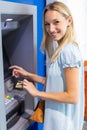 beautiful young blonde woman uses card in cash machine