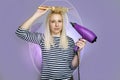 Beautiful young blonde woman using hairdryer and brush Royalty Free Stock Photo