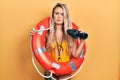 Beautiful young blonde woman wearing bikini and holding lifeguard float and binoculars relaxed with serious expression on face Royalty Free Stock Photo