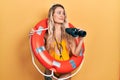 Beautiful young blonde woman wearing bikini and holding lifeguard float and binoculars smiling looking to the side and staring Royalty Free Stock Photo