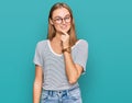 Beautiful young blonde woman wearing casual clothes and glasses looking confident at the camera with smile with crossed arms and Royalty Free Stock Photo